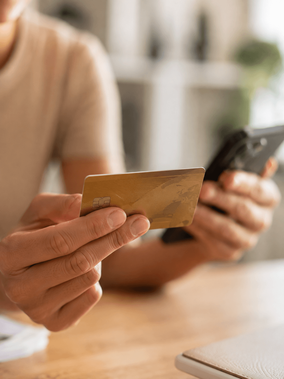 Pessoa com o cartão em uma mão e o celular na outra para pagar a parcela mensal do consórcio Ademicon em Joinville